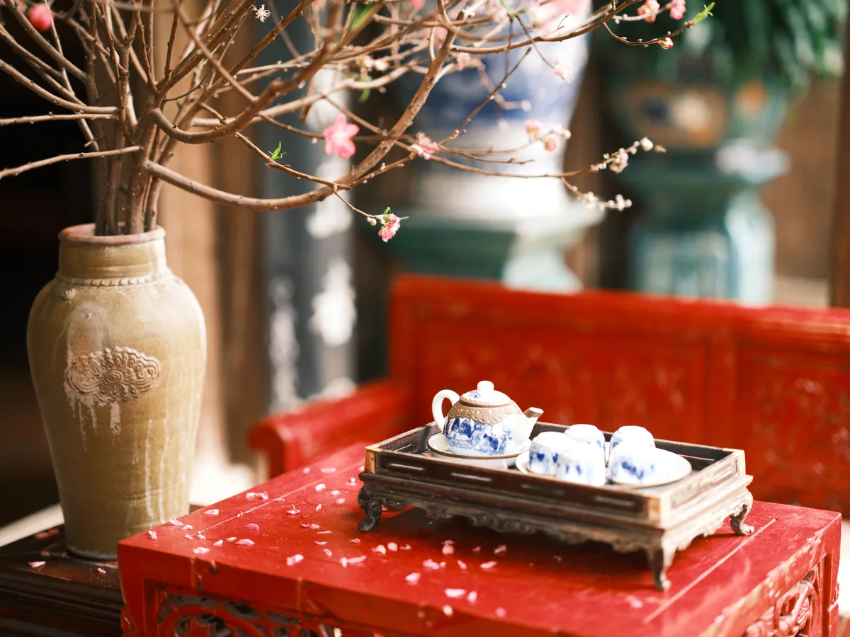 A Chinese tea set on a red lacquer table beside a flowering branch